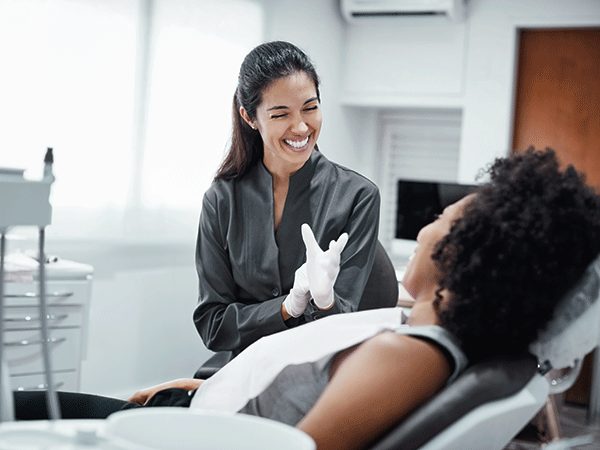 Dental hygienist smiling and talking to patient in chair